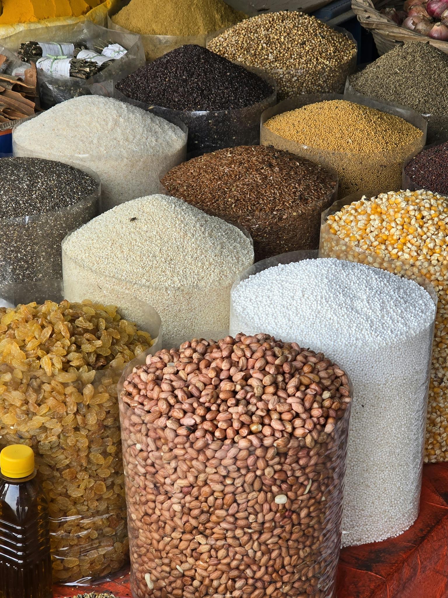 An array of grains and seeds on display in a Dhaka market, showcasing diverse textures and colors.